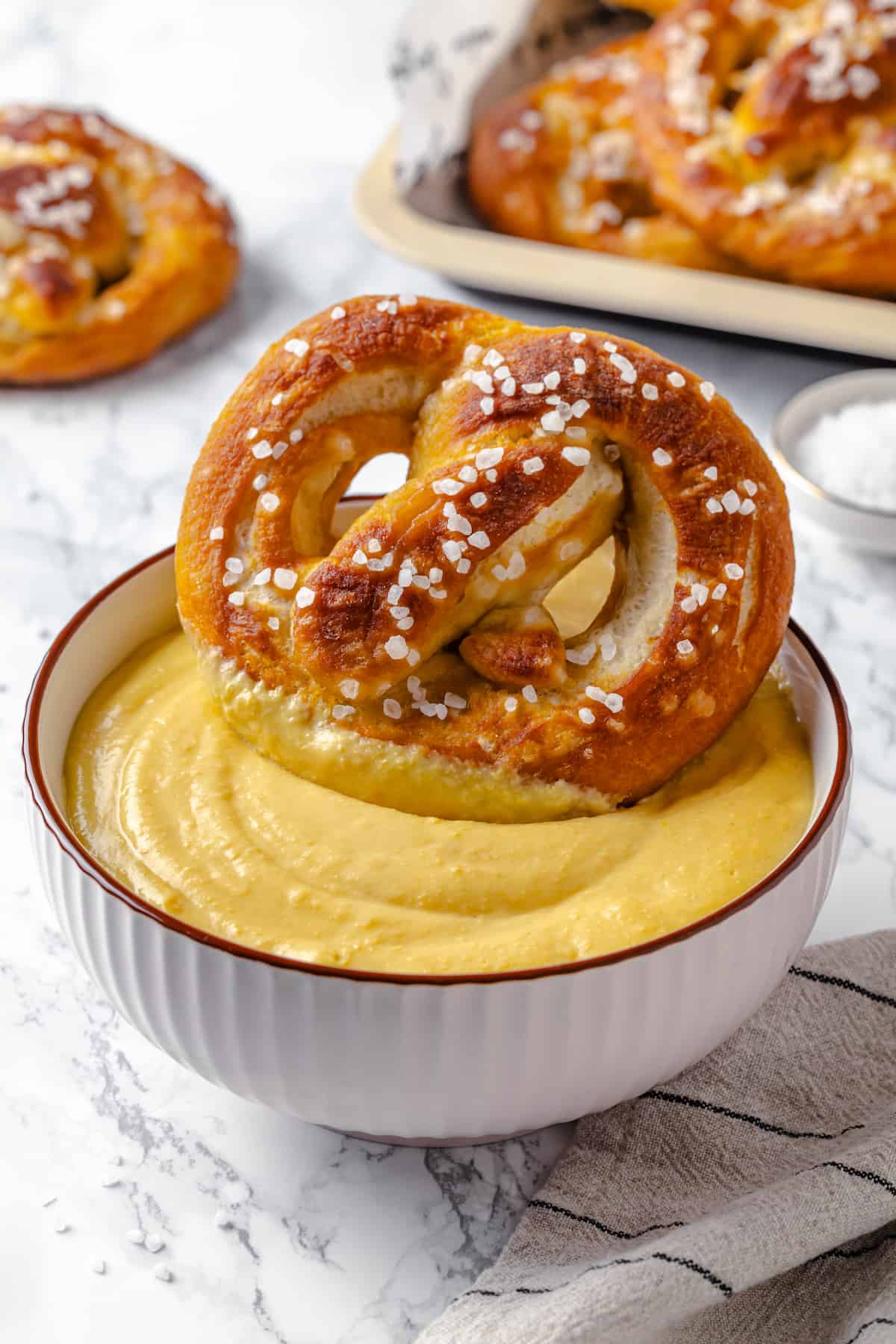 Vegan soft pretzel being dipped into beer cheese