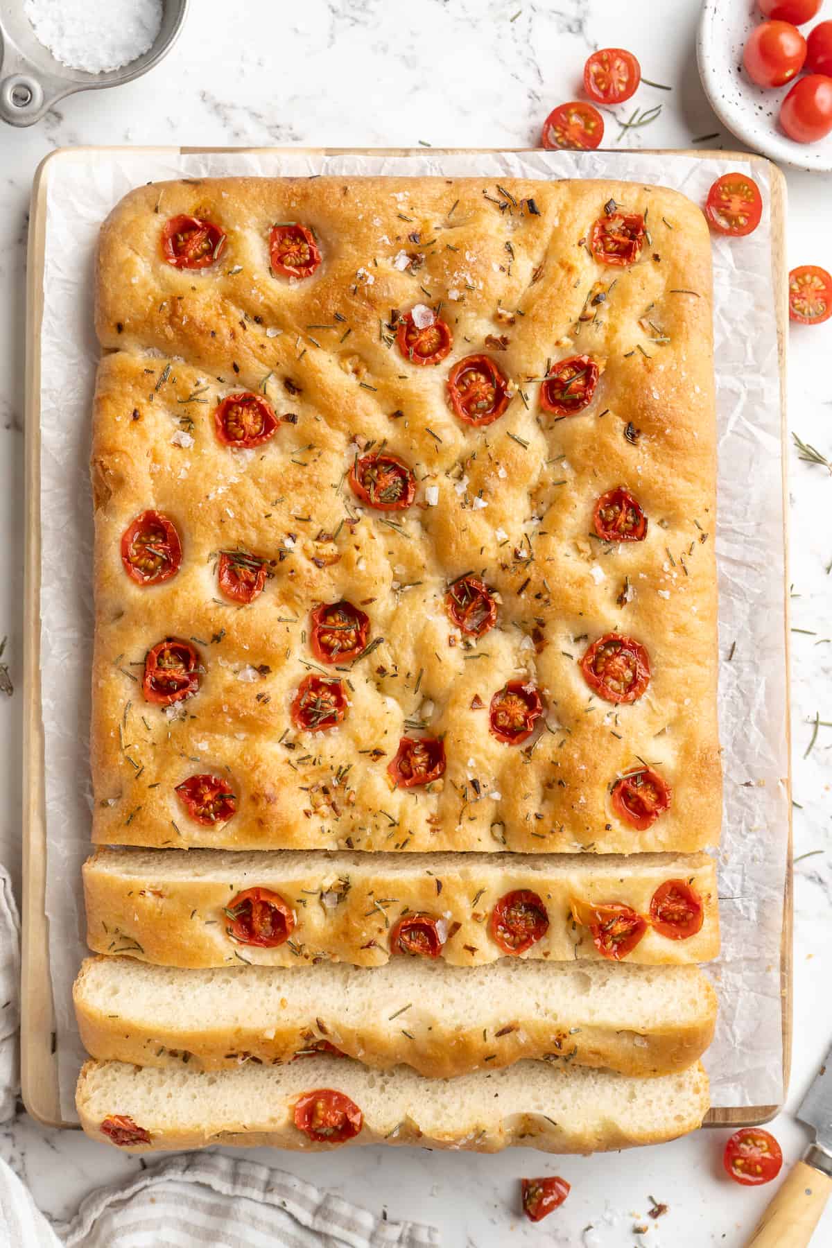 Half sliced gluten-free focaccia with tomatoes and rosemary