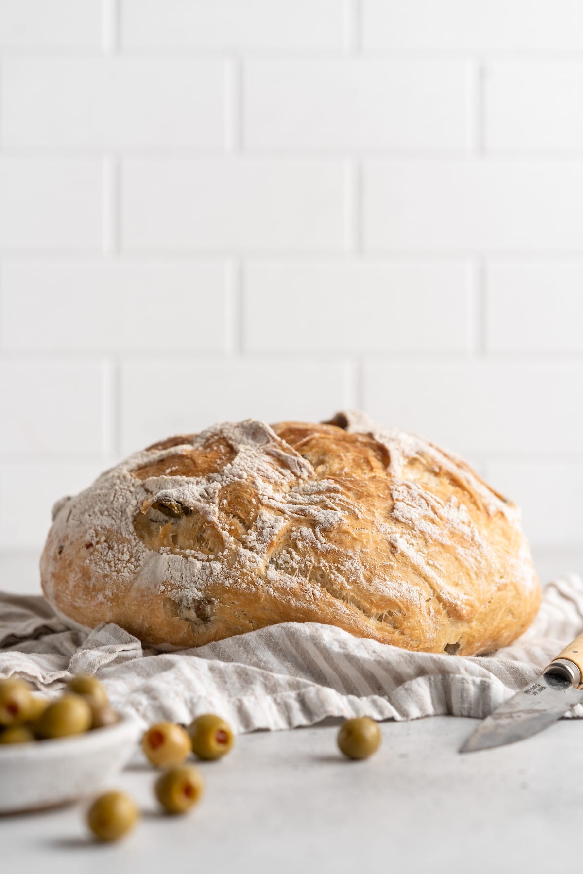 Whole olive bread loaf on tea towel