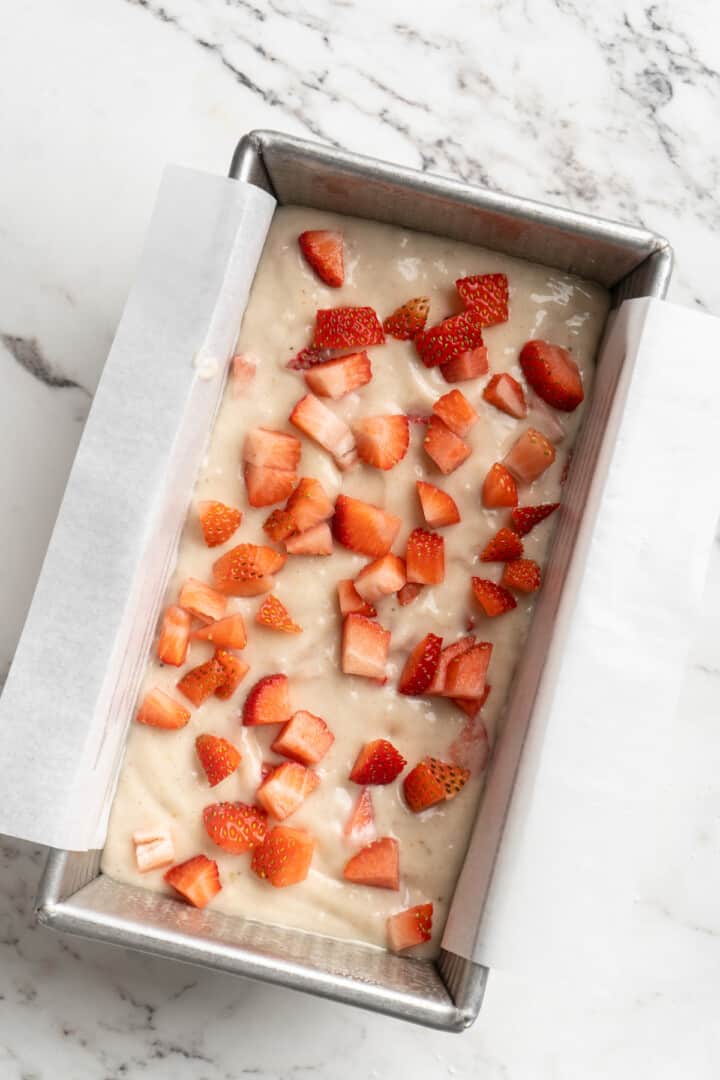 Overhead view of strawberries added to banana bread dough