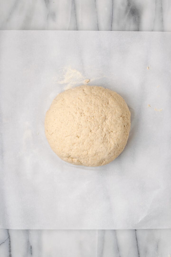 Overhead view of ball of dough on parchment paper