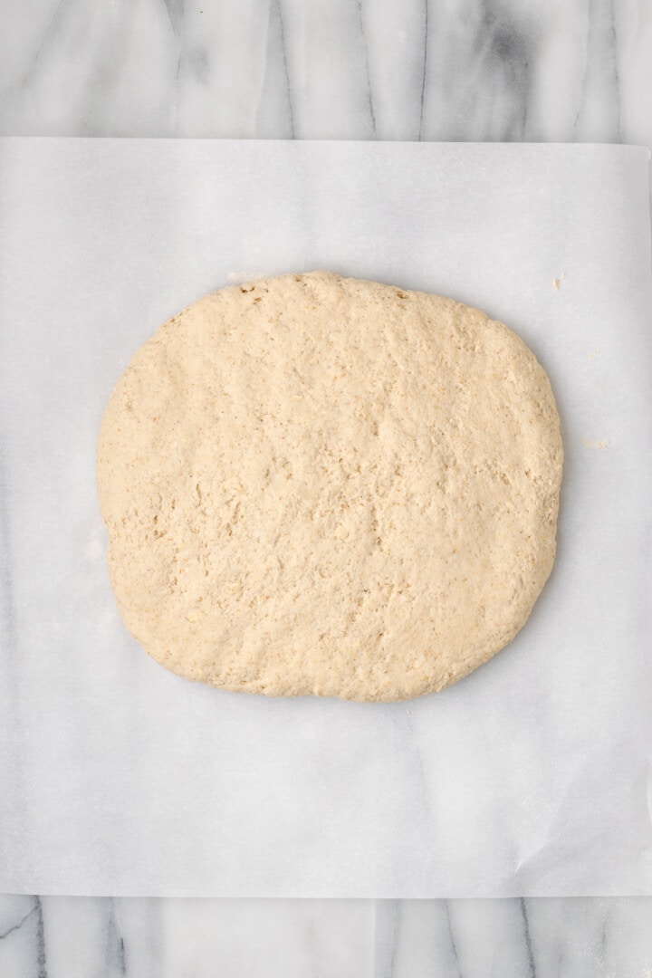 Overhead view of gluten-free sandwich bread dough flattened onto parchment paper