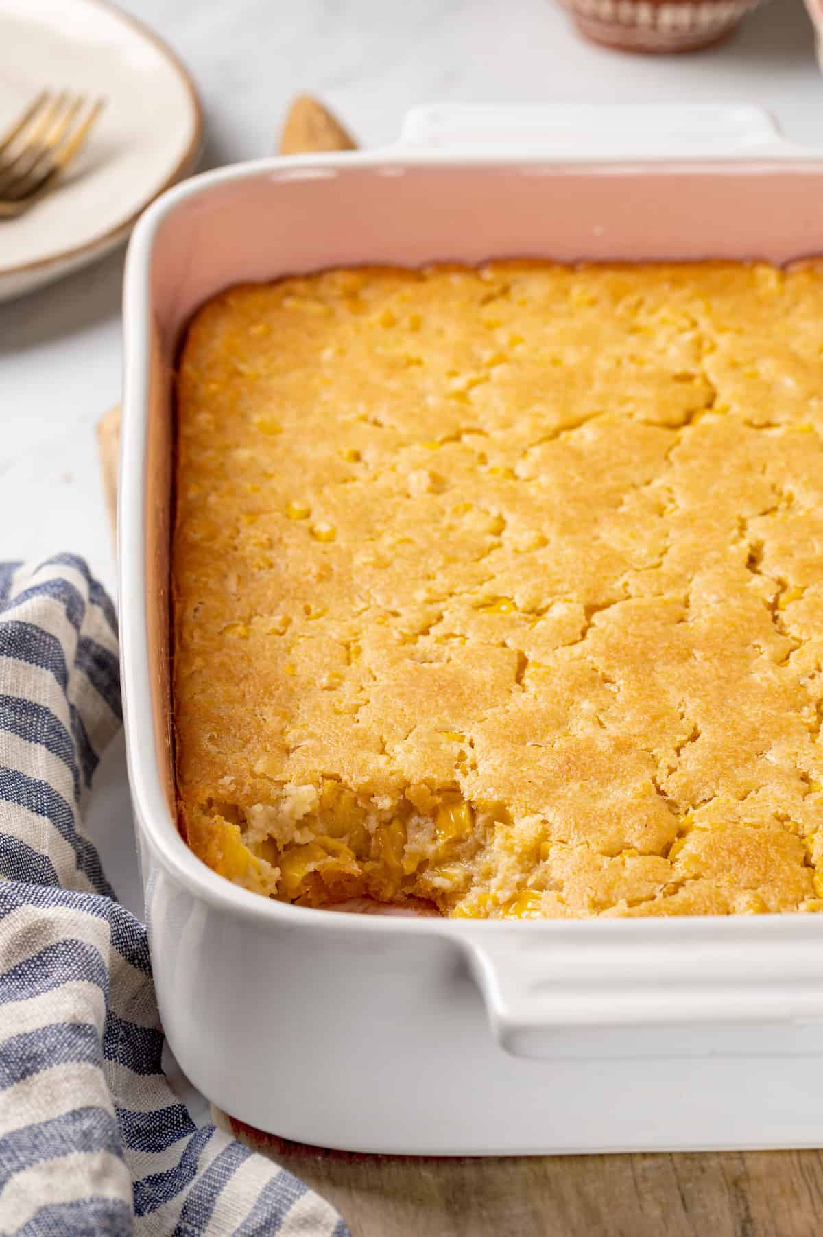 Corn souffle in baking dish with portion removed, showing fluffy texture