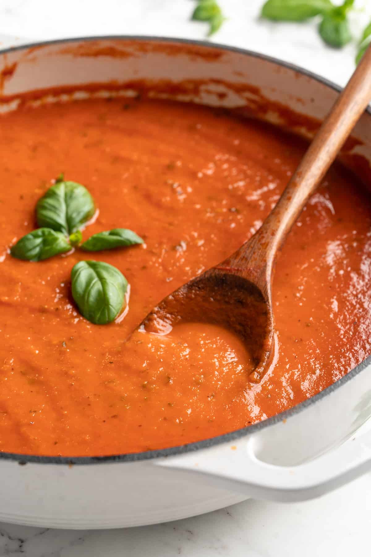 Pan of homemade tomato sauce garnished with basil