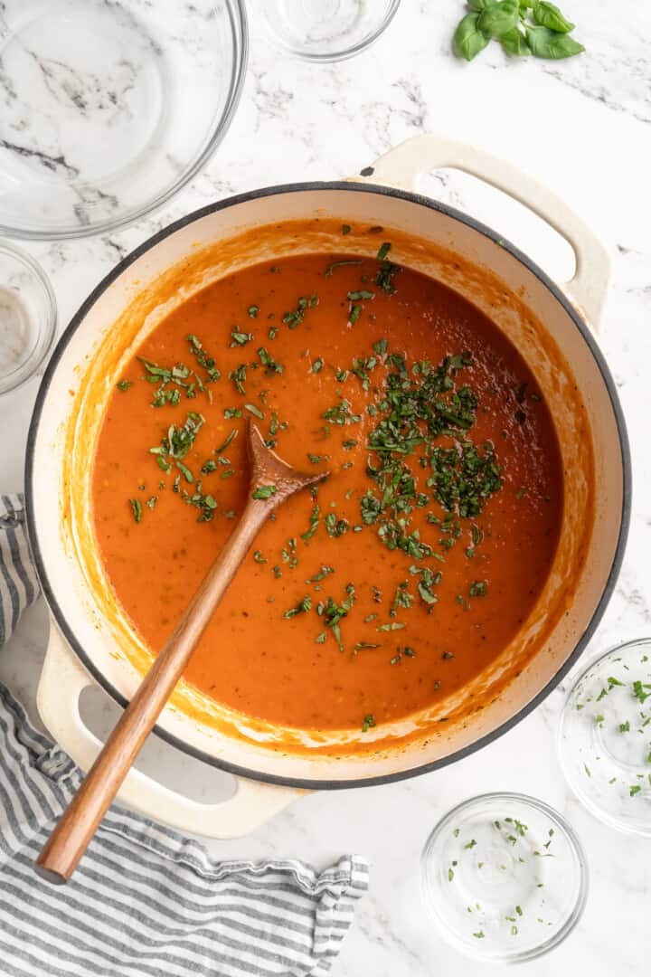 Stirring basil into homemade tomato sauce