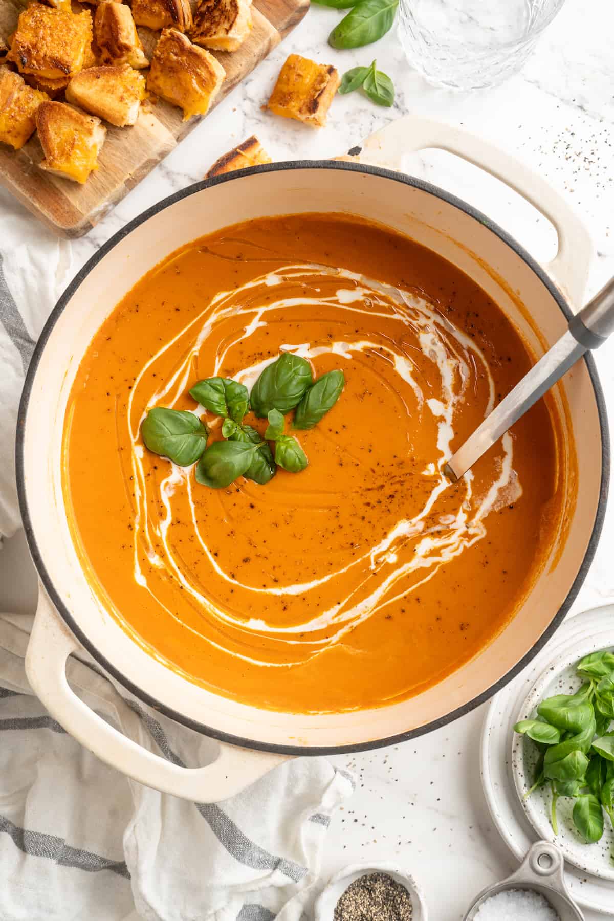 Overhead view of creamy tomato soup in pot with swirl of cashew cream