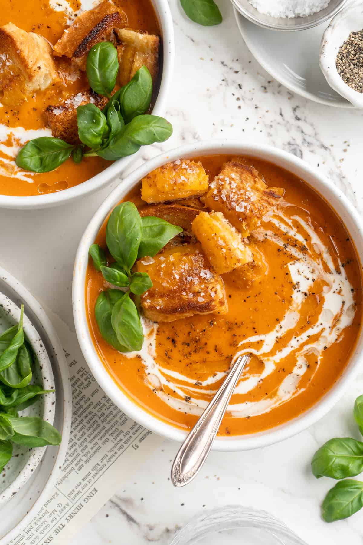 Overhead view of creamy tomato soup with cheesy croutons in bowls