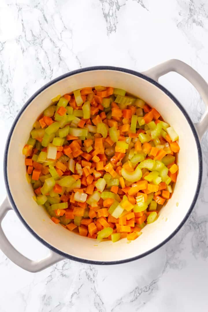 Overhead view of softened carrots, celery, and onions in pot