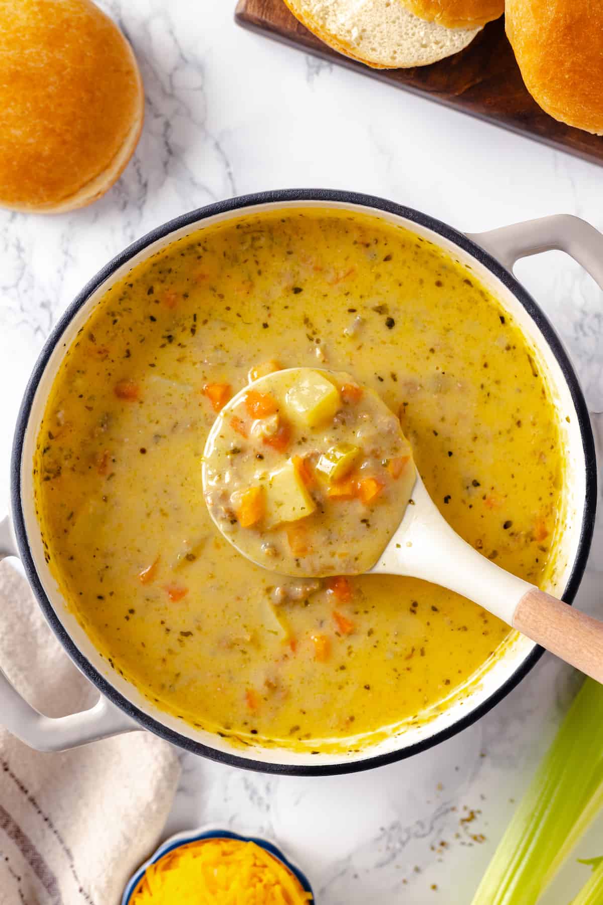 Ladle of creamy cheeseburger soup held over pot