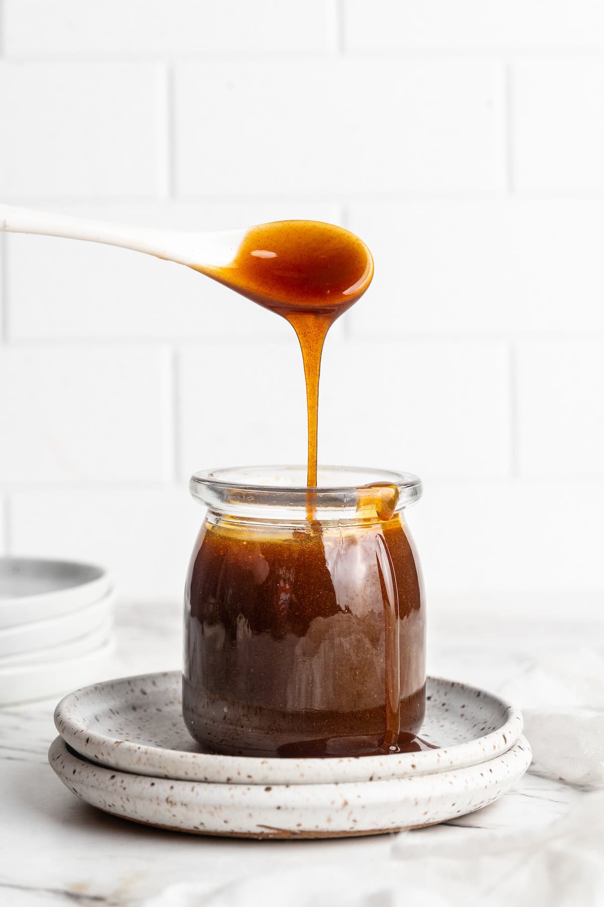 Spoon drizzling date syrup into glass jar