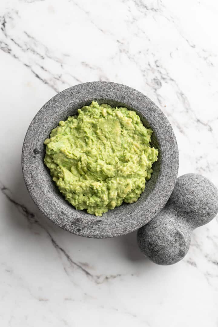 Overhead view of mashed avocado in molcajete