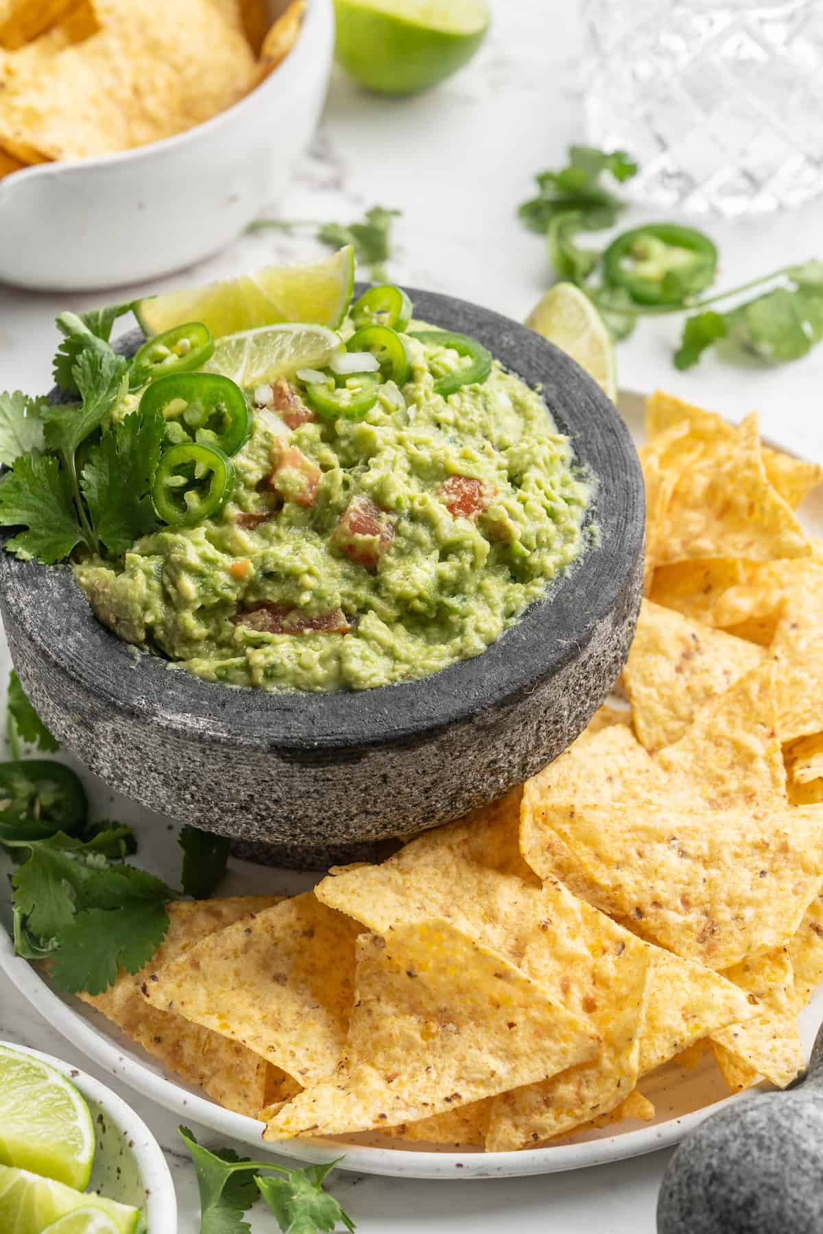 Molcajete with guacamole on plate with tortilla chips