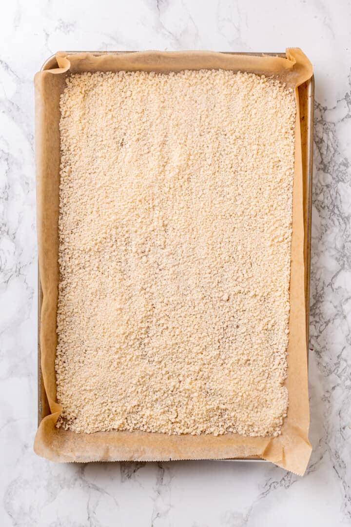 Vegan parmesan poured onto parchment lined baking sheet