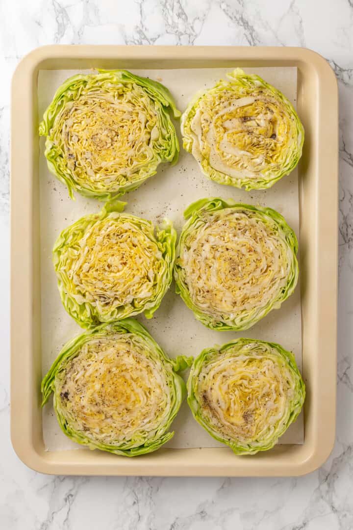 Overhead view of uncooked cabbage steaks on pan