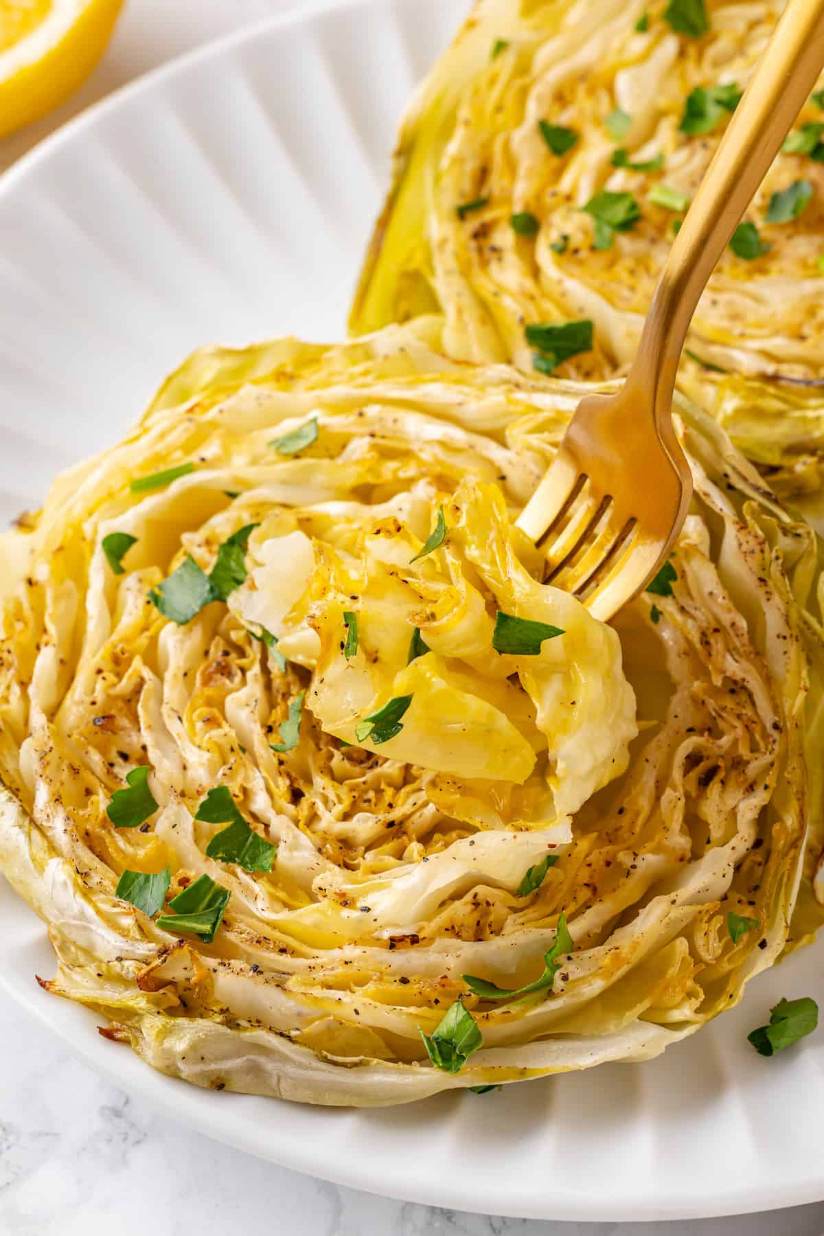 Two cabbage steaks on plate with gold fork