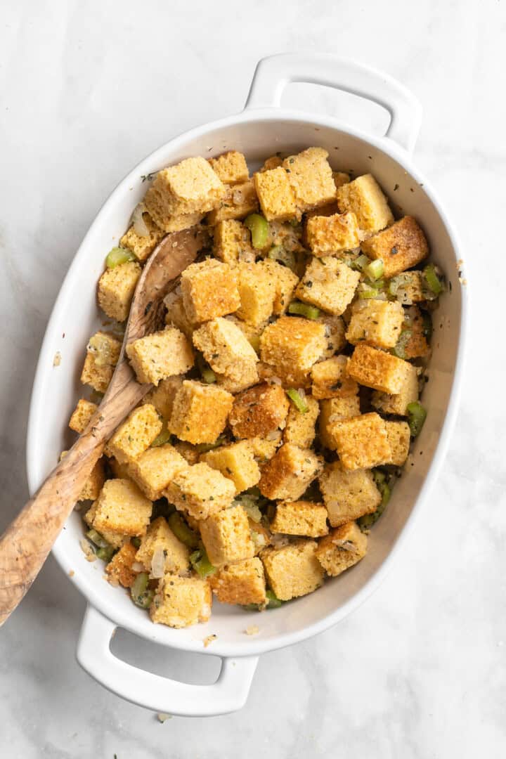 Stirring vegetables and cornbread in baking dish