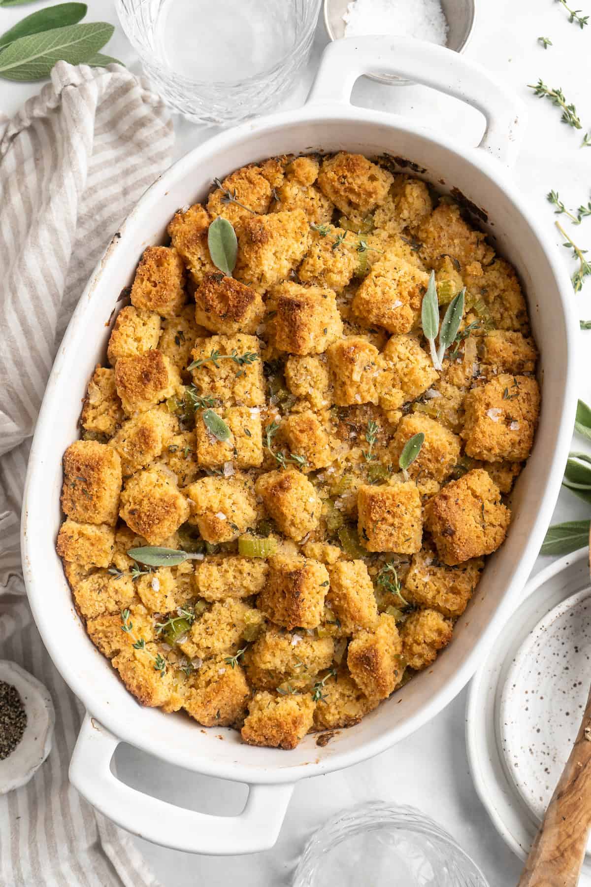 Overhead view of cornbread stuffing with fresh herbs in baking dish