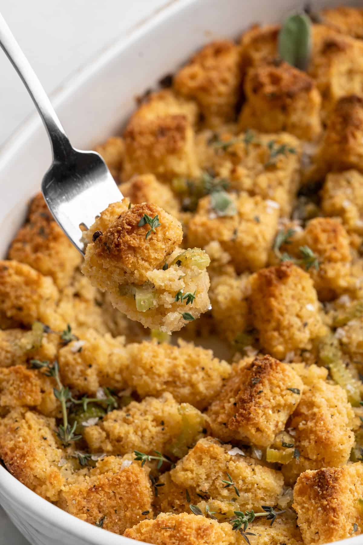 Forkful of cornbread stuffing held over baking dish