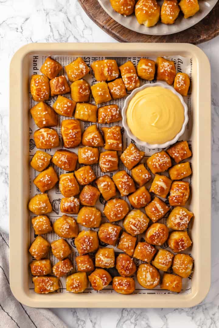 Overhead view of vegan pretzel bites on pan with cheese dip