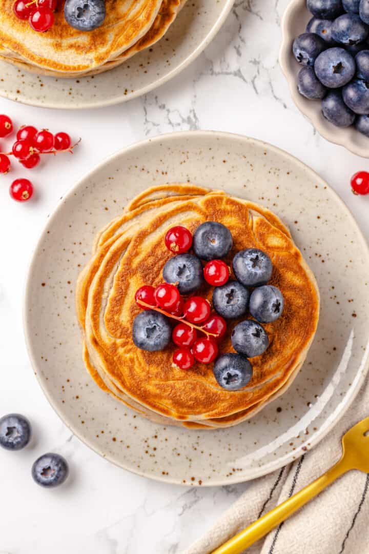 Overhead view of protein pancakes on plate with berries on top