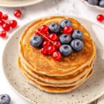 Stack of protein pancakes on plate with fresh berries on top