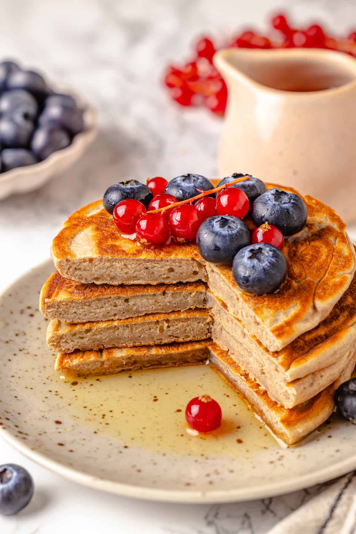 Stack of protein pancakes on plate, cut to show fluffy texture