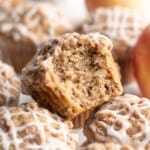 Apple streusel muffin with bite taken out on top of additional muffins