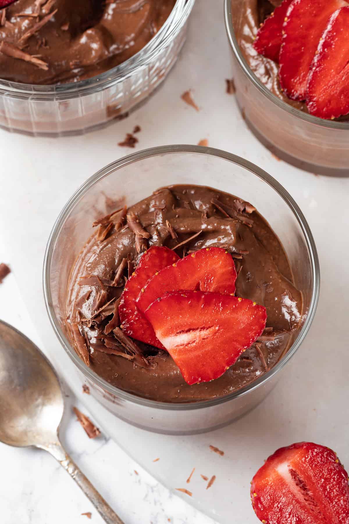 Overhead view of chocolate avocado mousse in glass ramekin with strawberry slices