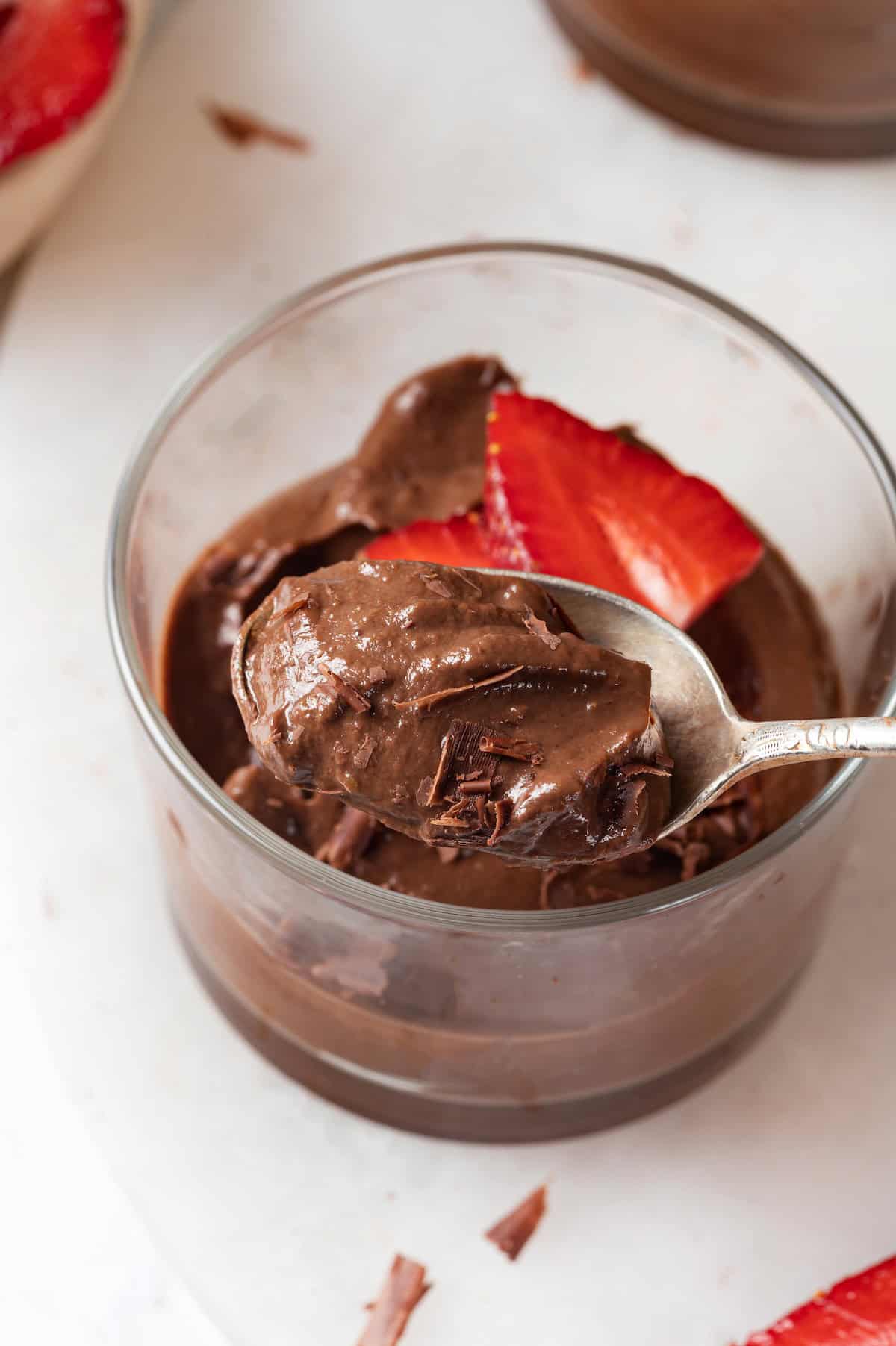 Ramekin of chocolate avocado mousse with spoon digging in