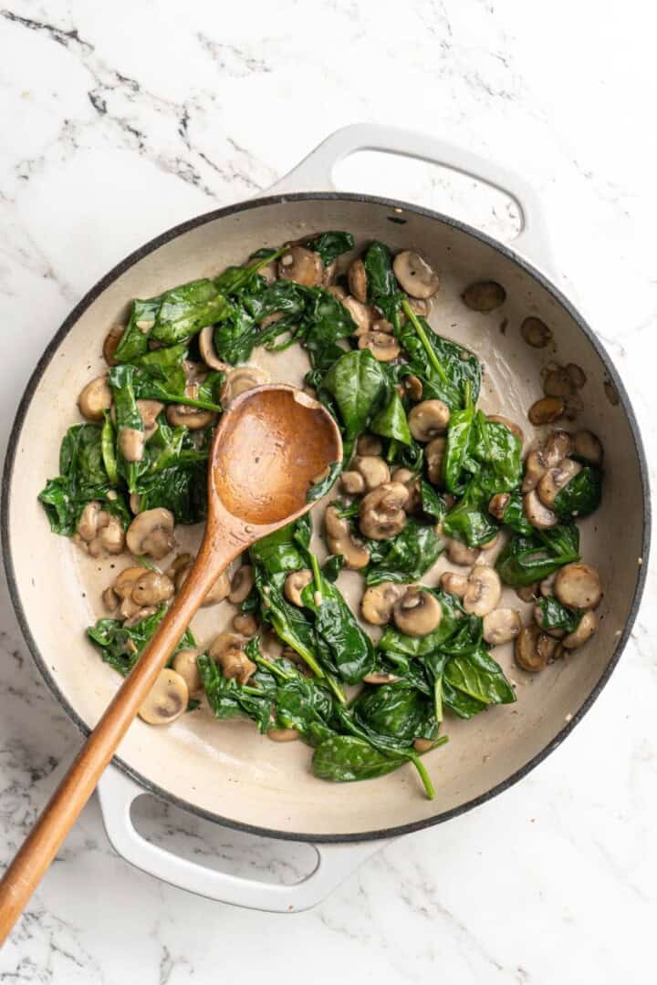 Overhead view of spinach and mushrooms in skillet