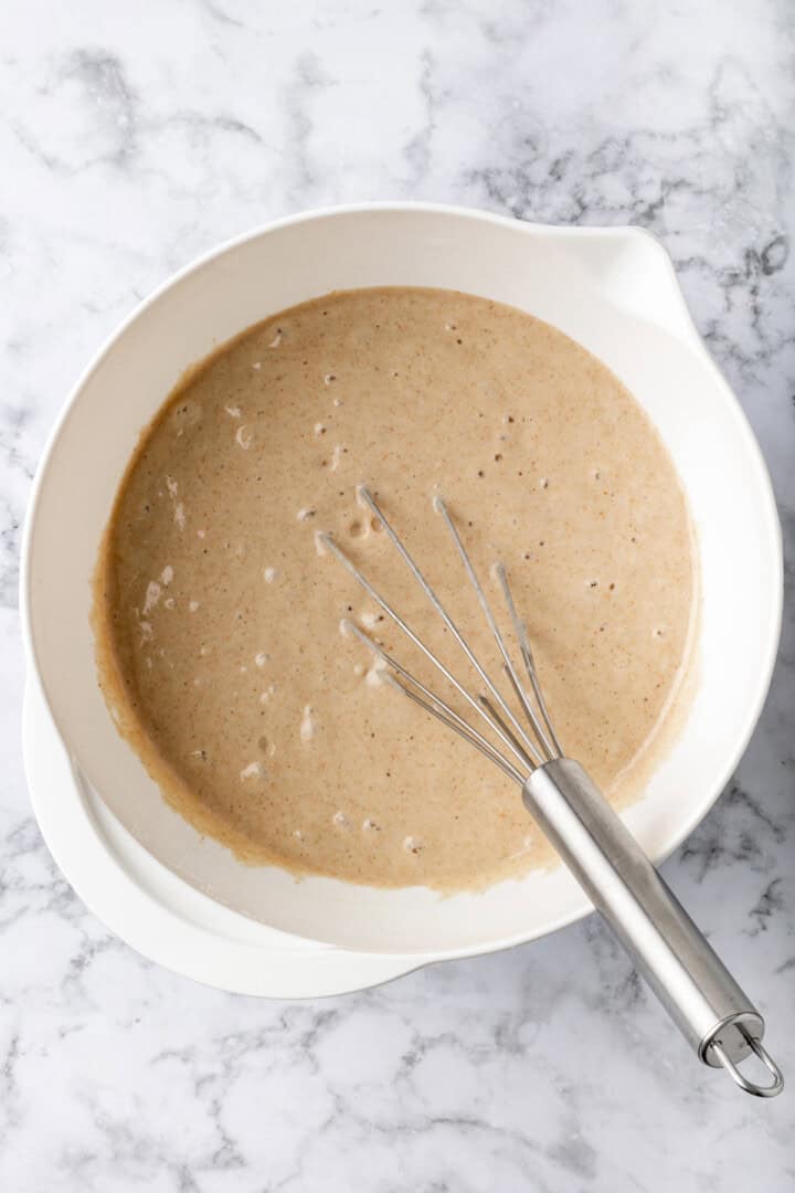 Overhead view of buckwheat pancake batter in mixing bowl with whisk