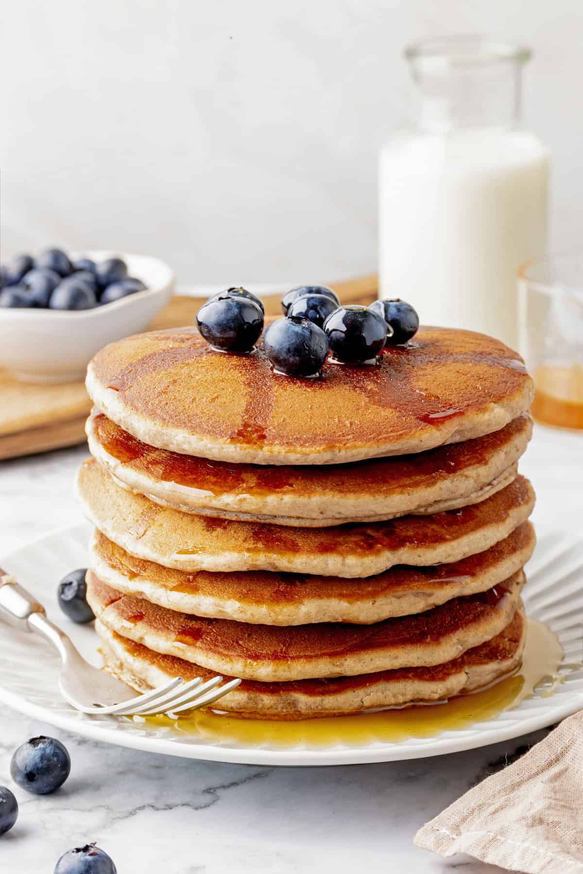 Stack of buckwheat pancakes topped with maple syrup and blueberries