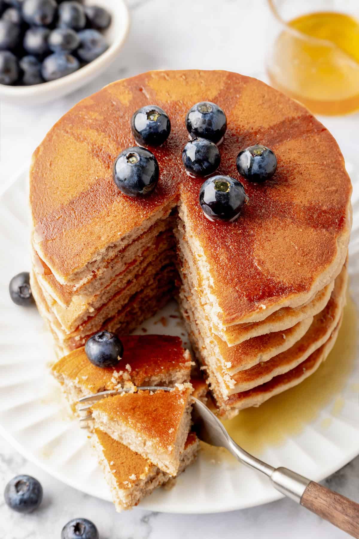 Stack of buckwheat pancakes topped with maple syrup and blueberries