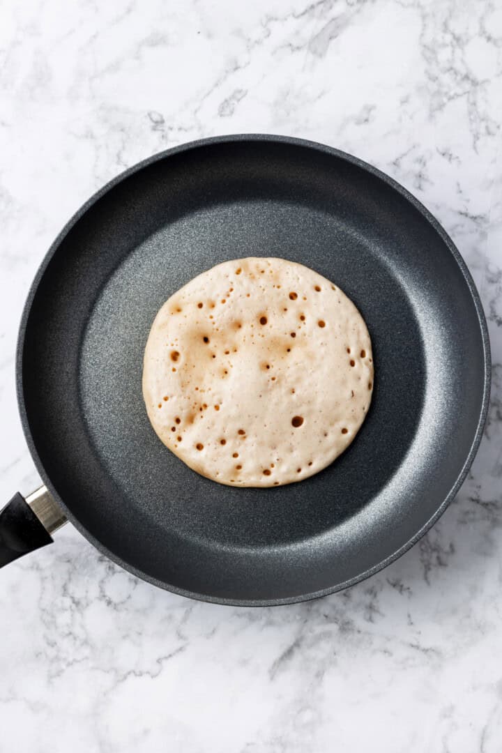 Overhead view of buckwheat pancake cooking in skillet