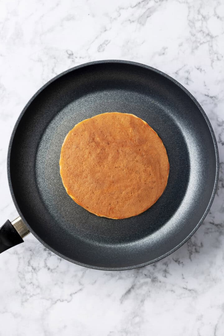 Overhead view of buckwheat pancake cooking in skillet