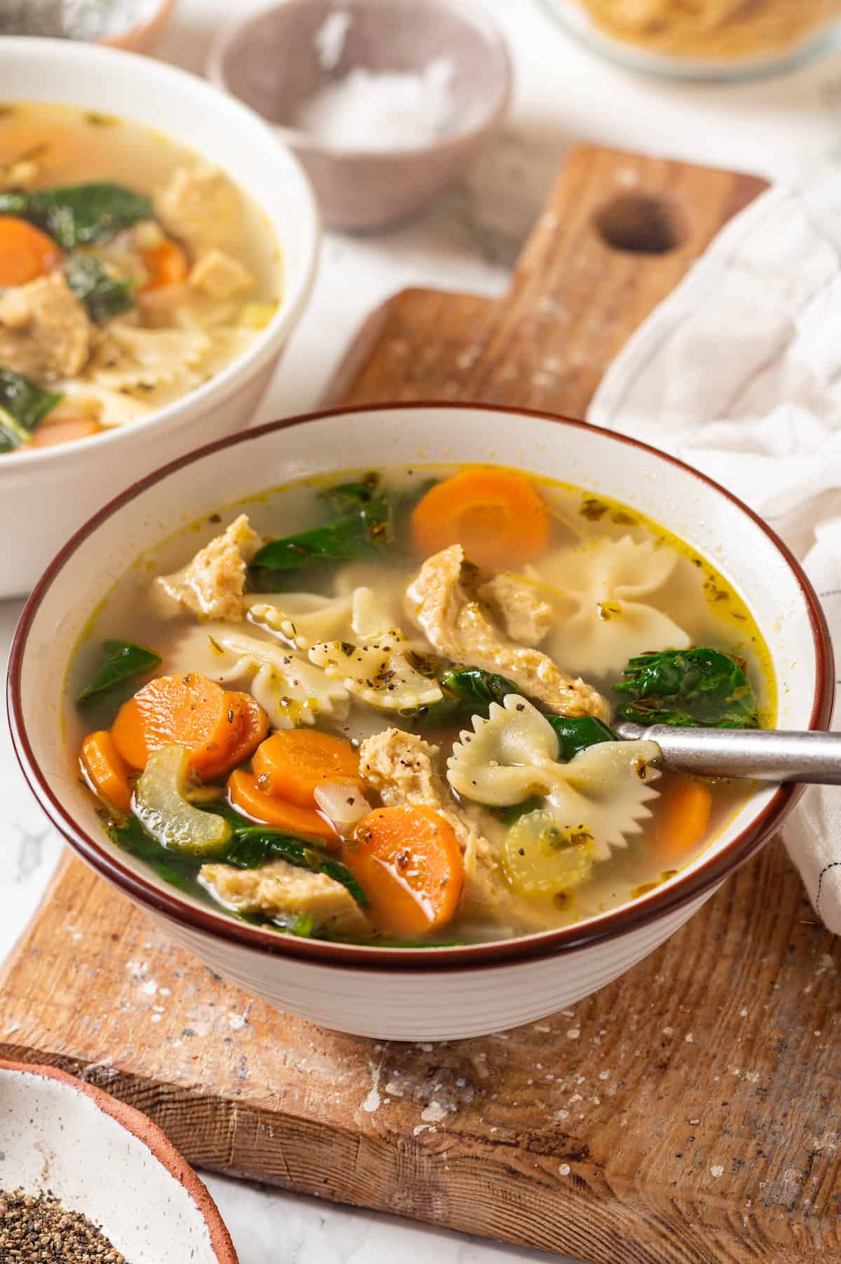 Homemade vegan chicken noodle soup in bowl on cutting board