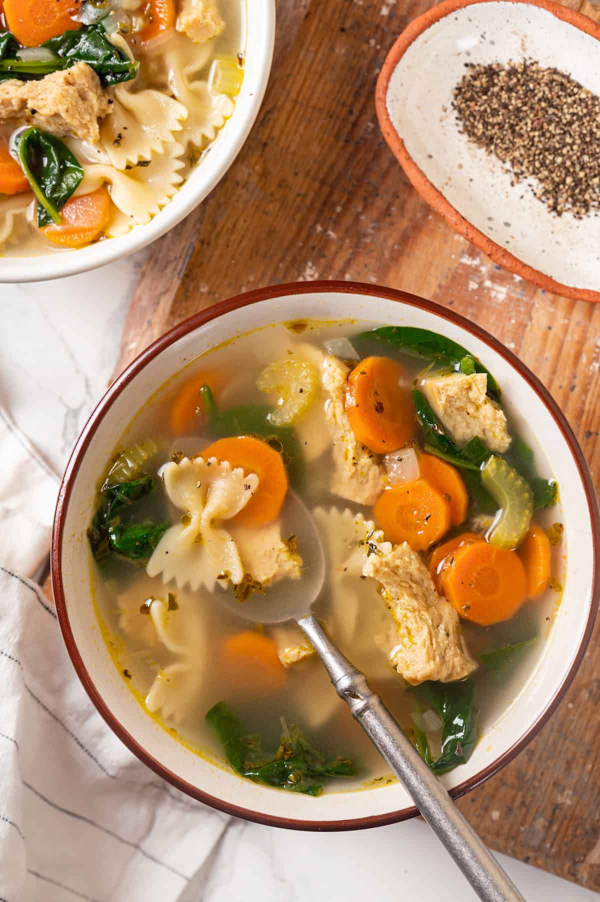 Overhead view of vegan chicken noodle soup in bowl with spoon