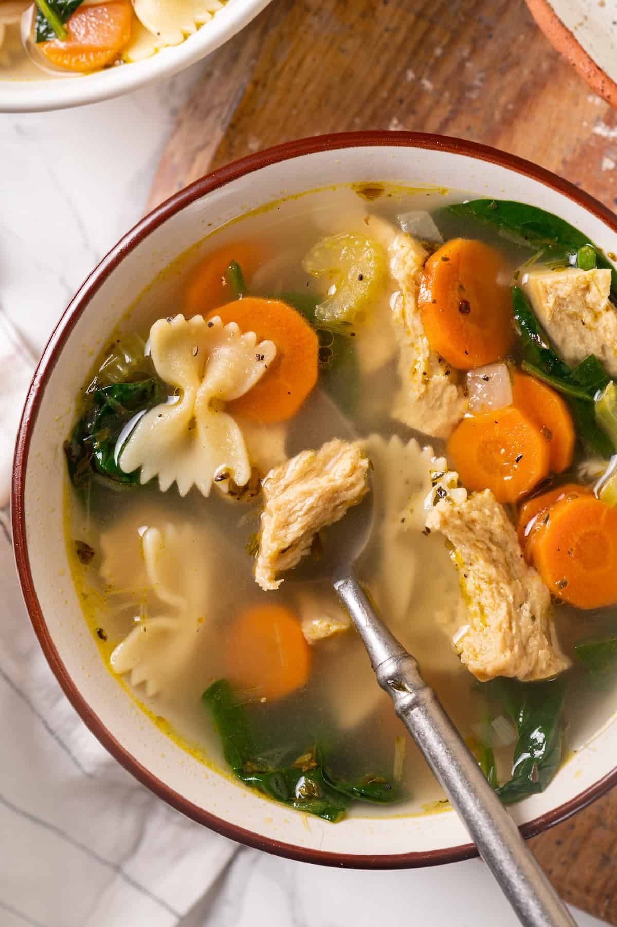 Overhead view of vegan chicken noodle soup in bowl with spoon