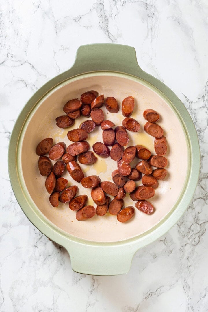 Overhead view of vegan sausage cooking in skillet