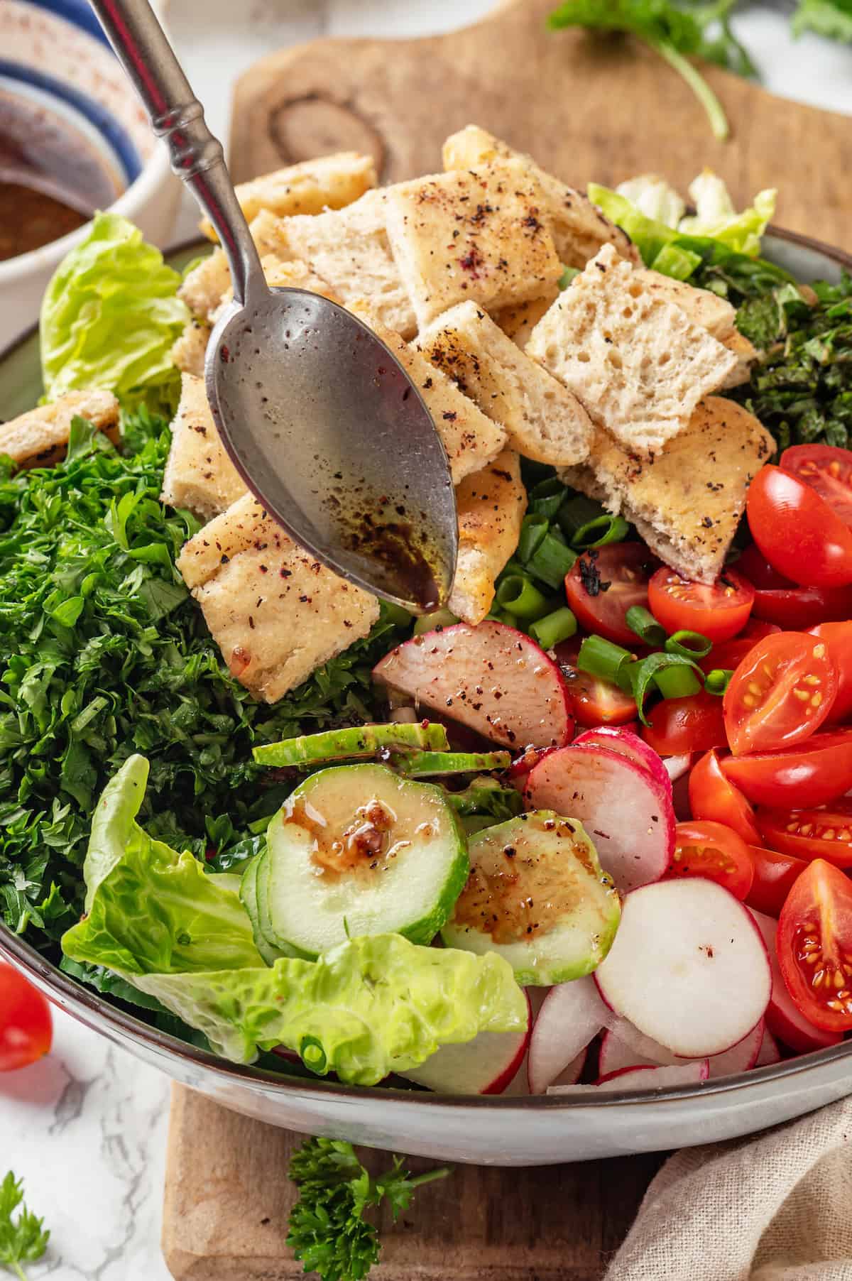 Drizzling dressing onto fattoush salad