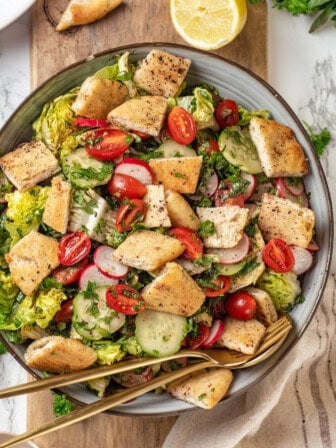 Overhead view of fattoush salad in serving bowl with spoon and fork
