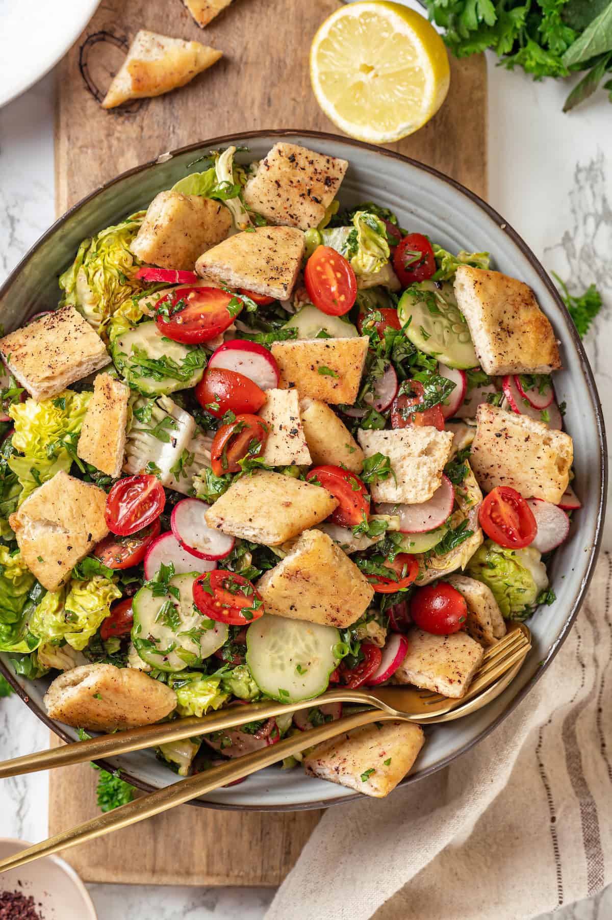 Overhead view of fattoush salad in serving bowl with spoon and fork