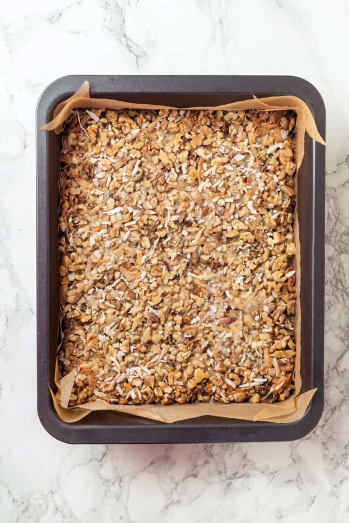 Overhead view of seven layer bars in parchment lined pan