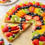 Cut fruit pizza with one slice pulled away