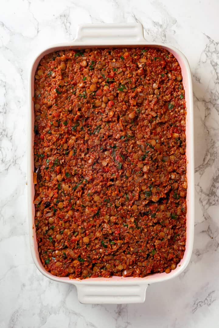 Overhead view of lentils and sauce added to vegan moussaka