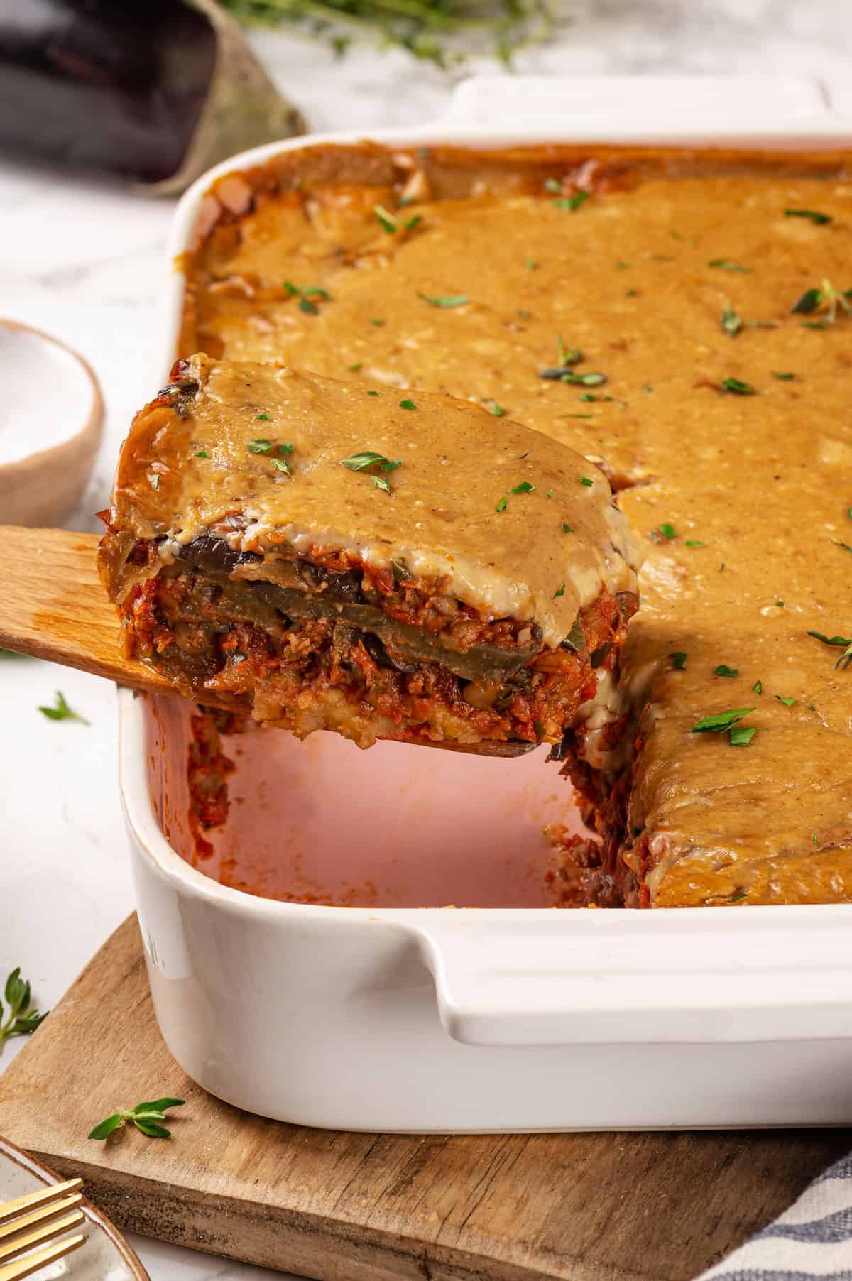 Removing portion of vegan moussaka from baking dish