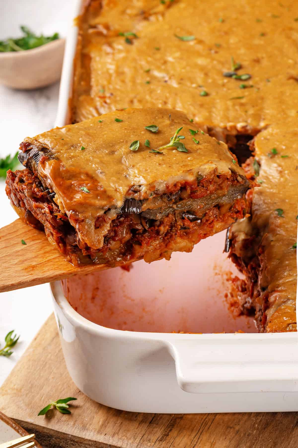 Taking vegan moussaka portion out of pan