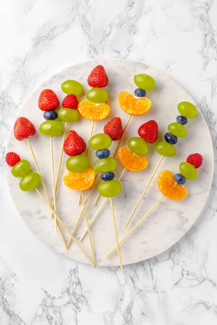 Overhead view of fruit skewers on marble slab