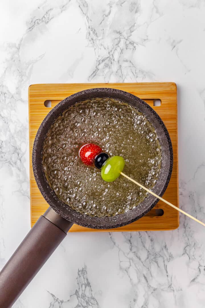 Dipping fruit skewer into sugar mixture