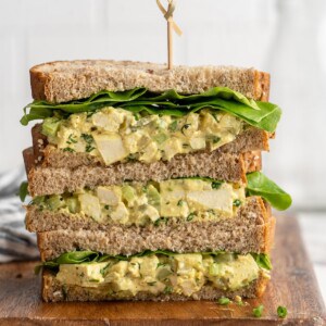 3 stacked tofu egg salad sandwiches on cutting board